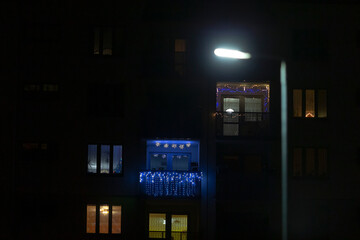 Naklejka premium A visually unclear photograph of a tall building taken at night, with a street light illuminating the foreground area, creating a moody atmosphere