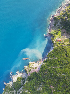 Aerial view of the rugged coastline where turquoise waters meet the verdant cliffs of Isola del Tino, a symphony of nature's hues, Porto Venere, Liguria, Italy.