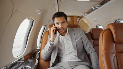 Surprised businessman conversing on his cellphone while seated in luxurious leather seats of a private jet, enjoying the convenience and privacy of exclusive air travel - Powered by Adobe