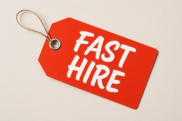 A red tag with the words "FAST HIRE" in bold white letters, attached to a string, symbolizing quick employment opportunities or urgent recruitment needs.