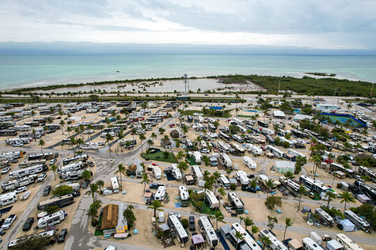 Aerial view of RVs clustered like gleaming beetles on sandy lots near the Overseas Highway, with turquoise waters beyond the lush, green vegetation, Big Pine Key, Florida, United States.