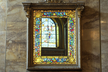 Fototapeta premium Fine detailed Greek stained window behind translucent Roman mirror