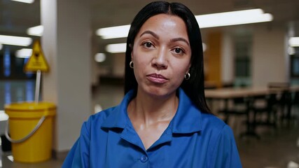 Close-up of latina nurse in blue scrubs looking confidently at camera in clinical environment