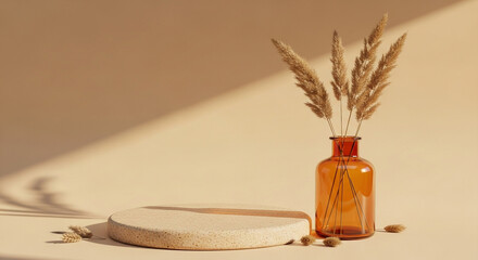 Fototapeta premium A minimalist composition featuring a round textured pedestal, an amber glass vase with dried pampas grass, and scattered almonds on a neutral background with soft shadows