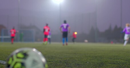 A dynamic soccer match takes place on a foggy field, capturing closeups of the ball and players navigating the mist, showcasing intense teamwork - Powered by Adobe