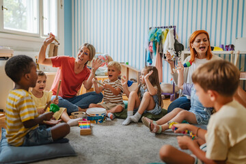 Diverse group of preschool children and teachers playing musical instruments in a colorful kindergarten classroom, engaging in fun early education and creative learning activities