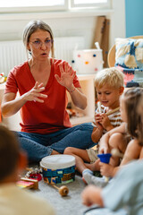 Preschool teacher leading a diverse group of children in a fun music activity, playing instruments...