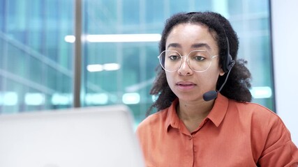 African american female corporate operator in headset working in customer support service on helpline telesale talking using laptop in business office. Agent of call center advises client. Close up - Powered by Adobe