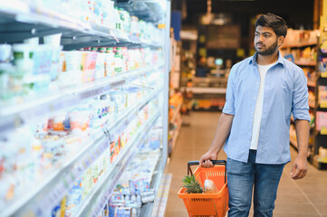 Young indian man choosing groceries in supermarket