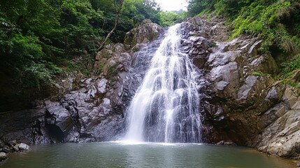 Obraz premium Majestic waterfall cascading down rocky cliffs into a tranquil pool.