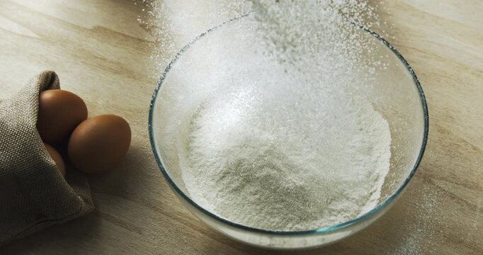 Slow Motion Flour Falling into Glass Bowl. Baking Ingredient Preparation on Rustic Kitchen Table, Ideal for Homemade Bread, Pastry, or Traditional Pasta Dough Recipes at 1000 fps.