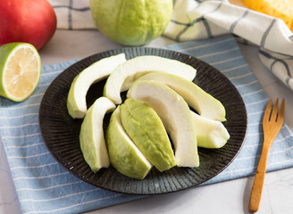 Fresh Guava Slices on a Plate with Lime and Wooden Fork side view of healthy fruit snack