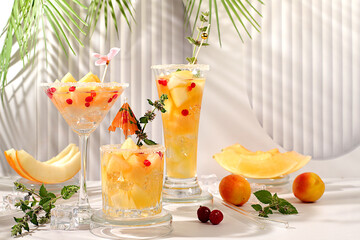 Melon alcoholic or non-alcoholic cocktail with mint. Martini, mojito and royal sangria with melon slices, ice, mint and currants. Summer party concept, advertising for a bar or cafe, detox diet