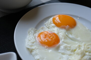 Chili pepper arranged breakfast plate with fried egg and cherry tomatoes on white dish, set on yellow background with green checkered napkin, concept of healthy eating, morning