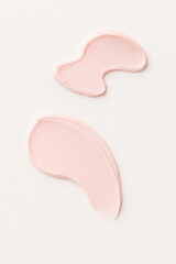 Close-up image of two pastel light pink cream smears on a clean white background. The product is evenly textured, perfect for cosmetic branding, skincare product presentations, advertising purposes