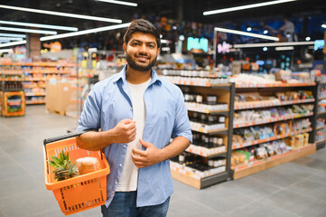 Indian man holding shopping basket in grocery store