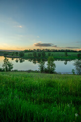 A stunning golden hour sunset over a tranquil lake, with a powerful sunburst and strong lens flares, highlighting the reflections on the water and a treeline