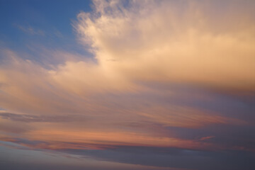 Obraz premium Ethereal twilight sky with a painterly canvas of soft, wispy clouds in warm sunset hues of orange and pink.