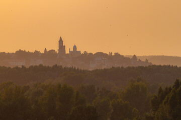 Sunset view from Kalemegdan Fortress – orange haze bathes forested riverbanks and the distant...