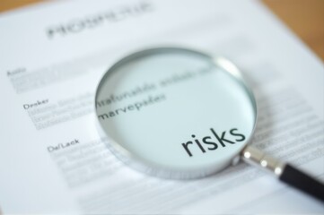 magnifying glass highlights word "risks" on financial document. business and finance report. risk assessment and analysis.