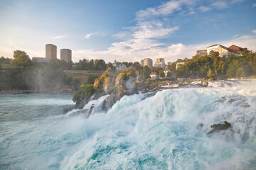 Majestic Rhine Falls cascading through lush greenery at sunset near Schaffhausen