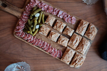 Gourmet Charcuterie Board with Sliced Salami Bread and Pickles on Wooden Platter