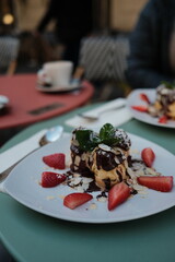 Delicious Dessert Display with Chocolate Drizzled Profiteroles and Fresh Strawberries in a Cafe