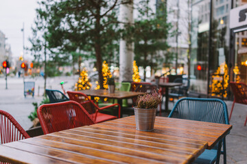 Cozy Outdoor Cafe Seating with Festive Lights in Urban Setting Surrounded by Lush Greenery and Warm Ambiance at Dusk