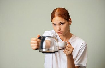 Young woman in white t shirt, gripping empty coffee pot with worried expression, lamenting lack of morning caffeine