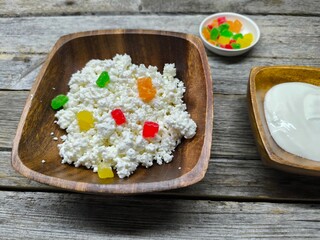 Homemade traditional cottage cheese organic dairy product in wooden bowl, next to it is a cup of sour cream