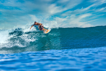 Male surfer on a blue wave at sunny day