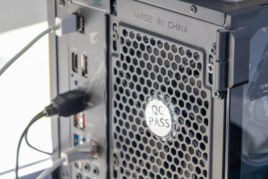 Close up of back panel of computer case showing ports, cables, and qc pass sticker