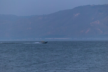 Obraz premium Evening twilight views of the Sea of Galilee in Israel with calm waters, distant mountains, boats, and serene blue tones creating a peaceful atmosphere