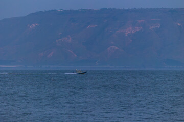 Obraz premium Evening twilight views of the Sea of Galilee in Israel with calm waters, distant mountains, boats, and serene blue tones creating a peaceful atmosphere