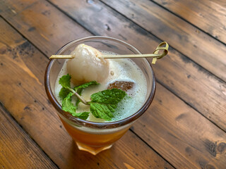 Glass of ice lychee tea garnish with Fresh Lychee and Mint on a wooden table