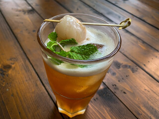 Glass of ice lychee tea garnish with Fresh Lychee and Mint on a wooden table