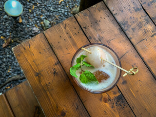 Glass of ice lychee tea garnish with Fresh Lychee and Mint on a wooden table