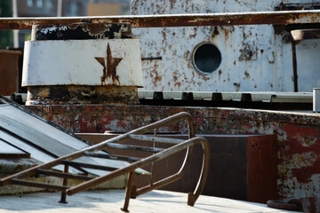 Rusty star emblem on old ship chimney with weathered surfaces and industrial details