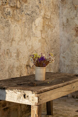 Wildflowers in a vase on a rustic wooden table.