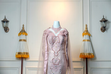 A graceful pastel pink wedding gown with intricate lace embroidery and beaded details, displayed on a mannequin, exuding elegance, romance, and luxury style.