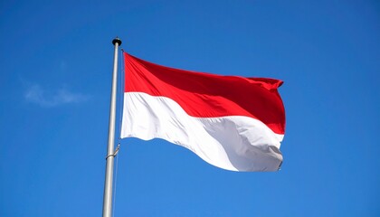 "Indonesian flag waving on a pole, red over white horizontal stripes, set against a bright blue sky with scattered clouds."