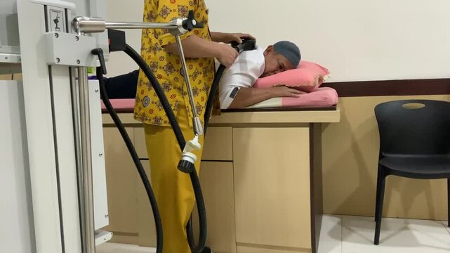 Senior man receiving Transcranial Magnetic Stimulation with nurse assistance