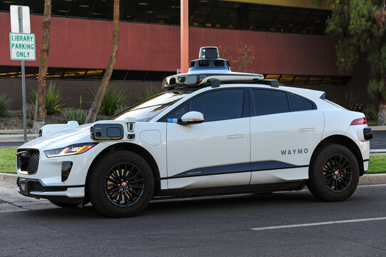 Waymo autonomous Jaguar electric SUV equipped with roof and side sensors parked roadside, representing self-driving vehicle technology and transportation innovation