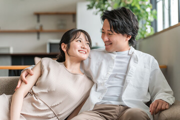 家のリビングでソファーに座る若いアジア人夫婦
