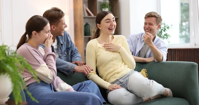 Friends laughing on sofa indoors. Positive emotion