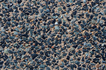 Small blue stones in exposed aggregate concrete close-up abstract textured background