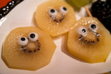 Quirky slices of kiwi fruit with cartoonish eyes, creating a playful and humorous presentation on a plate.