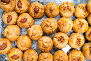 Delicious baked cookies topped with nuts, featuring a golden, glossy surface and a soft, fluffy texture, perfect for snacking or dessert