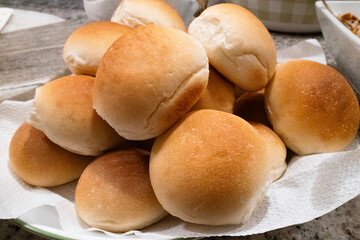Soft, golden-brown dinner rolls stacked on a plate, perfect for any meal, showcasing a fluffy texture and warm appearance