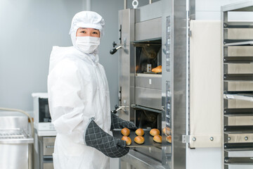 パン工場,食品工場で働く防塵服,クリーンスーツを着た製造スタッフの男性  © buritora